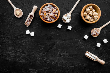 Brown and white sugar in bowls, scoop and spoon. Cane, refind, granulated, cubes, candy. Black background top view copy space