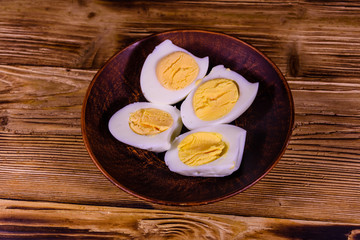 Ceramic plate with peeled boiled eggs on wooden table