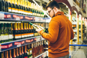 man choose alcohol in store. shopping concept. bottle in man hands