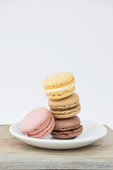 Macarrones o macaroons con platillo blanco sobre tabla madera