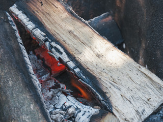 The wooden logs burn in the campfire before cooking a food on a picnic.