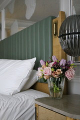 the bouquet of pink spring flowers of tulips and roses near the bed in the bedroom. hello spring, march
