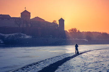 Krakow, Poland, photographer looking at Wawel Castle in the winter over frozen Vistula river,...