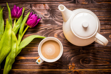 A cup of coffee with a teapot and flowers