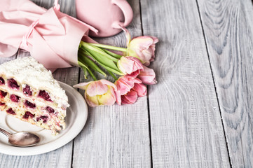 A cake with cherries and pink tulips on white wooden table