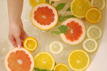 slices of citrus yellow lemon, orange and red grapefruit in the water of bath
