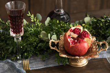 Wooden table with glass of wine green leaves and plate pomegranate