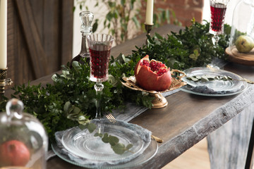 Wooden table with glass of wine green leaves and plate pomegranate