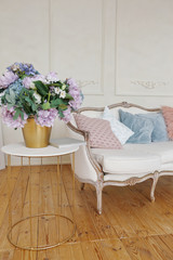 white sofa with pink and blue pillows near the white wall in spring luxury decorated appartment