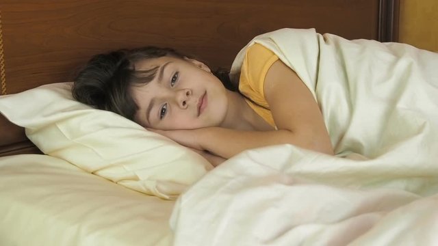 Child in bed. Beautiful girl lies in the bedroom.