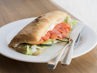 Sandwich with salmon on white plate on
