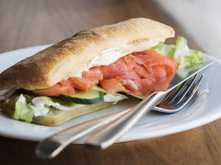 Sandwich with salmon on white plate on