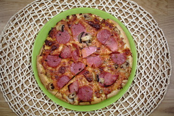 Pizza sliced on green plate. Closeup view. Food background.