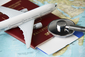 Boarding pass and a passport travel documents with medical stethoscope and airplane on world map...