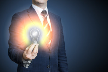 Hand of businessman holding illuminated light bulb, idea, innovation and inspiration concept. Bright idea in hand businessman