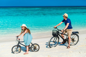 Fototapeta premium Father and daughter riding bikes at tropical beach