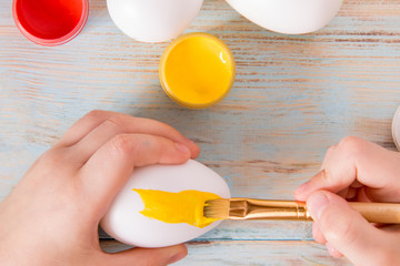 Preparation for Easter, little boy hands painted in yellow color Easter eggs