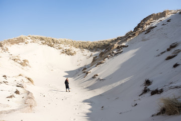blond teen girl in dunes of north holland on sunny winter day