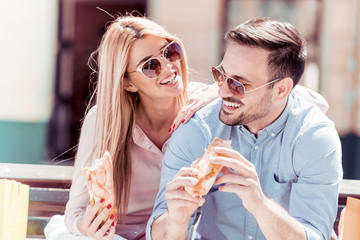 Couple eating sandwiches on a sunny day after shopping.