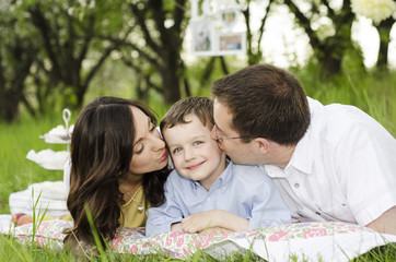 parents and child are laying on the grass