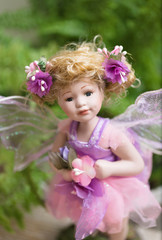 Fototapeta premium Lovely statuette, fairy doll in the fern foliage look beautiful eyes at you
