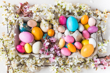 Fototapeta na wymiar Easter colorful chocolate candy eggs and spring flowers background, minimalism, modern decoration.