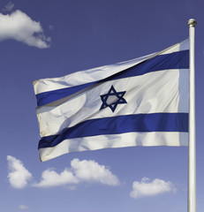 Israel flag flapping in the wind isolated against the blue sky. The flag is on a pole and flapping to the left. there are white clouds in the sky
