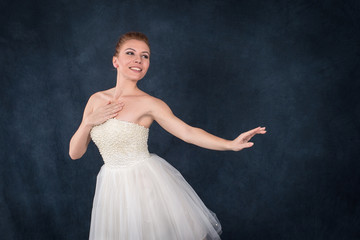 the ballerina in pointes and a white dress dances on a dark background