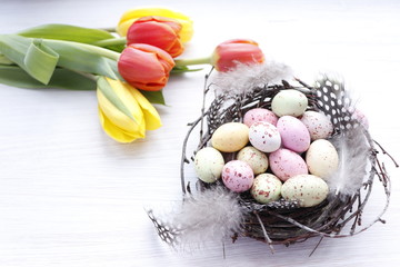 Easter background. Candy in the form of quail eggs and tulips. Selective focus.