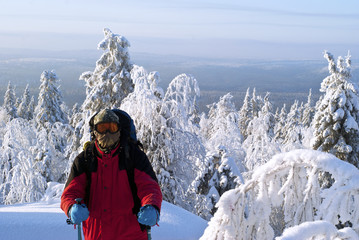 Fototapeta na wymiar traveler in warm clothes and a windproof mask, with a backpack, in a frosty winter mountain forest.