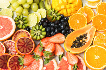 Healthy colourful fruits pattern background, strawberries, mango, grapes, bananas, grapefruit on the off white table, top view, selective focus