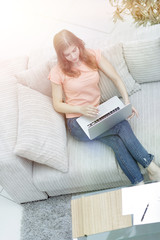 girl student with laptop sitting resting on the sofa.