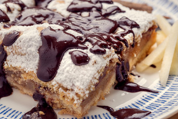 Freshly baked apple pie sprinkled with powdered sugar and topped with chocolate. Delicious homemade pastries with shallow depth of field.