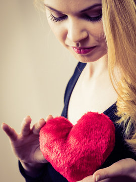 Nostalgic woman holding red heart