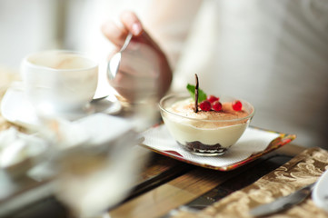 A newlywed couple drinking hot coffee or tea with sweet dessert in warm cozy cafe with wedding bouquet on the table. Atmoshere of happiness of new family and love tenderness