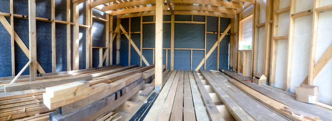 Building the frame of a wooden house. Panoramic picture inside the frame. Boards for flooring, vapor barrier walls.