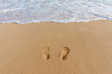 Fototapeta na wymiar pair of footprints in the sand and sea surf