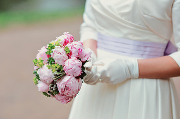 Obraz na płótnie Canvas Wedding bridal bouquet with pink peony in the hands of bride before wedding ceremony with decoration a lot of flowers and colorful tape shot taken by selective soft focus and macro
