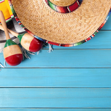 Mexico cinco de mayo background border square format with sombrero straw hat traditional rug or blanket and maracas on an old blue wood background fiesta carnival photo