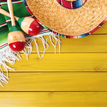 Mexico cinco de mayo background border square format with sombrero straw hat traditional rug or blanket and maracas on an old yellow pine wood background fiesta carnival photo