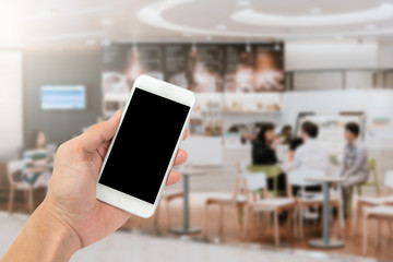 Hand holding smartphone in coffee shop