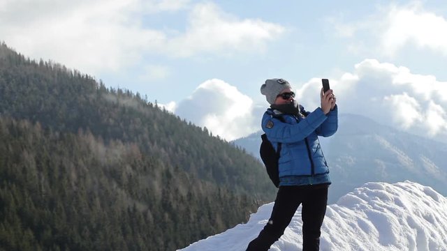 Young woman taking a self portrait with her smartphone in the mountains, Alps, Austria 