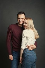 Portrait of a beautiful young couple in love posing at studio over dark background