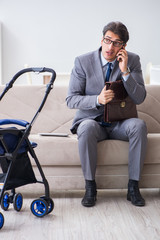 Businessman looking after newborn baby at home and teleworking
