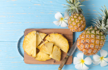 Fototapeta na wymiar sliced pineapple on wood block and blue wood