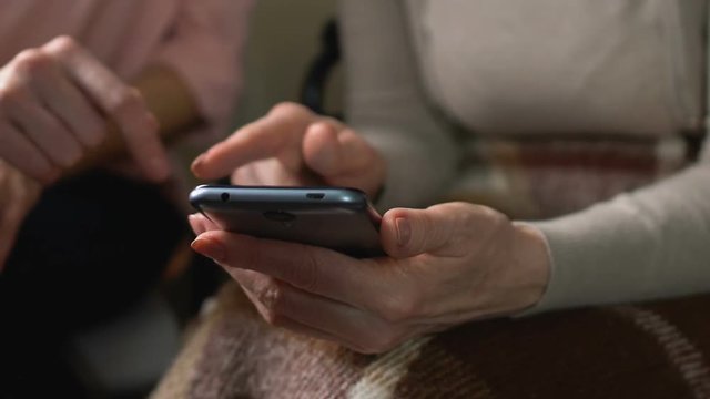 Daughter showing mother how to order food delivery at home using smartphone