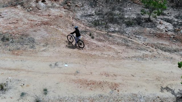 Woman riding mountain bicycle in the mountain park, Drone shot top view