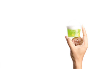 Hand holding plastic cup of sago in coconut milk with corn, Thai traditional dessert