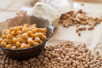 boiled and raw chickpea, peanuts and protein powder laying on a piece of craft paper