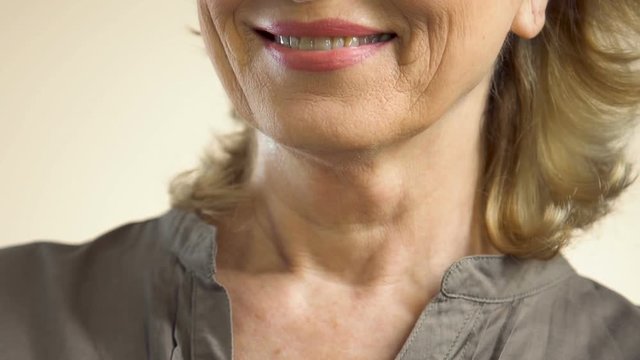 Happy middle-aged woman spraying perfume looking in mirror, going on date